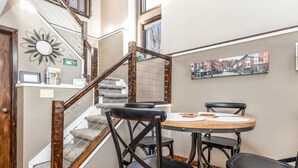 A staircase with wooden railings and carpeted steps leading to a dining area with a round table and four chairs. - Luxury, Golf-Themed Townhome (Galena)