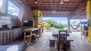 An outdoor patio with a brick oven, wooden furniture, and a hammock. - Casa Perto da Serra do Cip com Piscina e Sinuca (Jaboticatubas)