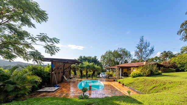 A pool area with a wooden deck, a covered seating area, and a view of the surrounding landscape. - Casa Perto da Serra do Cip com Piscina e Sinuca (Jaboticatubas)