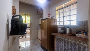 A kitchen with a refrigerator, coffee maker, and a window with a view. - Casa Perto da Serra do Cip com Piscina e Sinuca (Jaboticatubas)