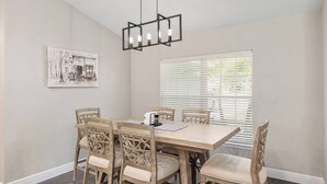 A dining room with a wooden table and chairs, a pendant light, and a window with blinds. - The Hobby Horse - 8 miles from WEC ! (Ocala)