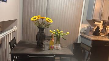 A dining table with two vases, one with sunflowers and one with tulips, and a bottle of wine.