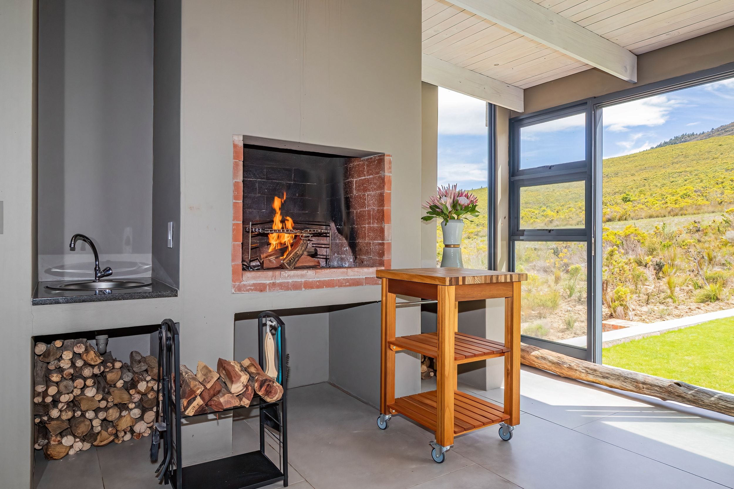 Een moderne keuken met een ingebouwde open haard, een spoelbak en een raam met uitzicht op een landschap.