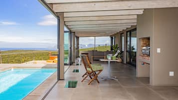 Een moderne buitenruimte met een zwembad, een zithoek en uitzicht op het landschap.