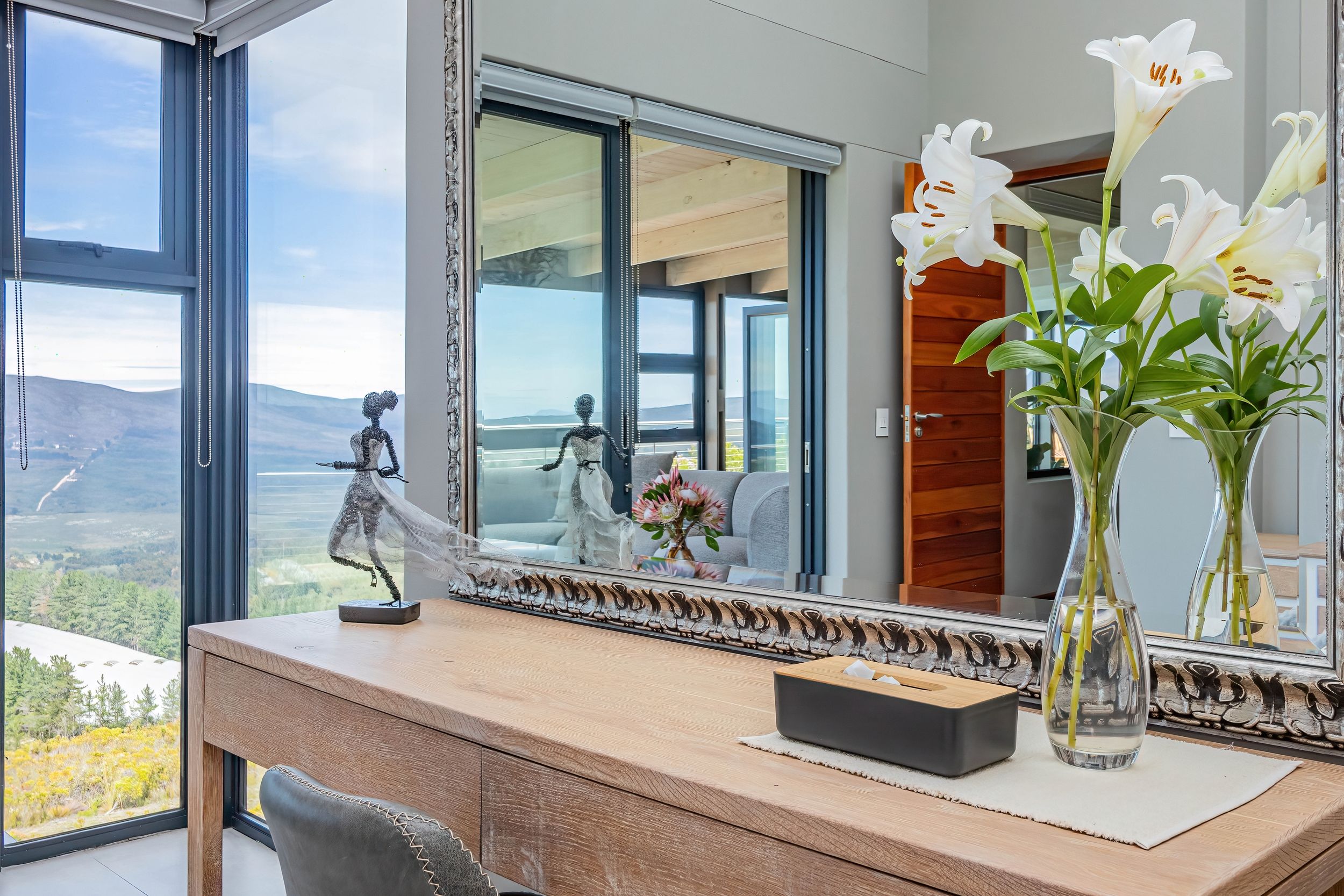 Ein modernes Interieur mit einem großen Fenster, einer Skulptur und einer Vase mit Blumen.