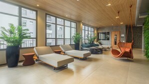 A modern lounge area with large windows, comfortable seating, and hanging chairs. - High-standard Studio 800m From the Metro Ihl0501 (São Paulo)
