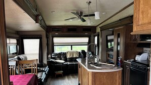 Interior compacto de uma motorhome, com cozinha compacta, área de refeições e espaço para sentar.