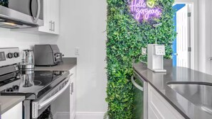 Une cuisine moderne avec des armoires blanches, une cuisinière en acier inoxydable et un néon mural.