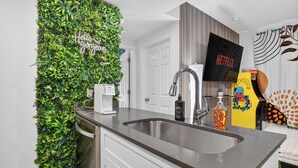 Une cuisine moderne dotée d’un mur végétal intégré, d’un évier en acier inoxydable et d’un logo Netflix.