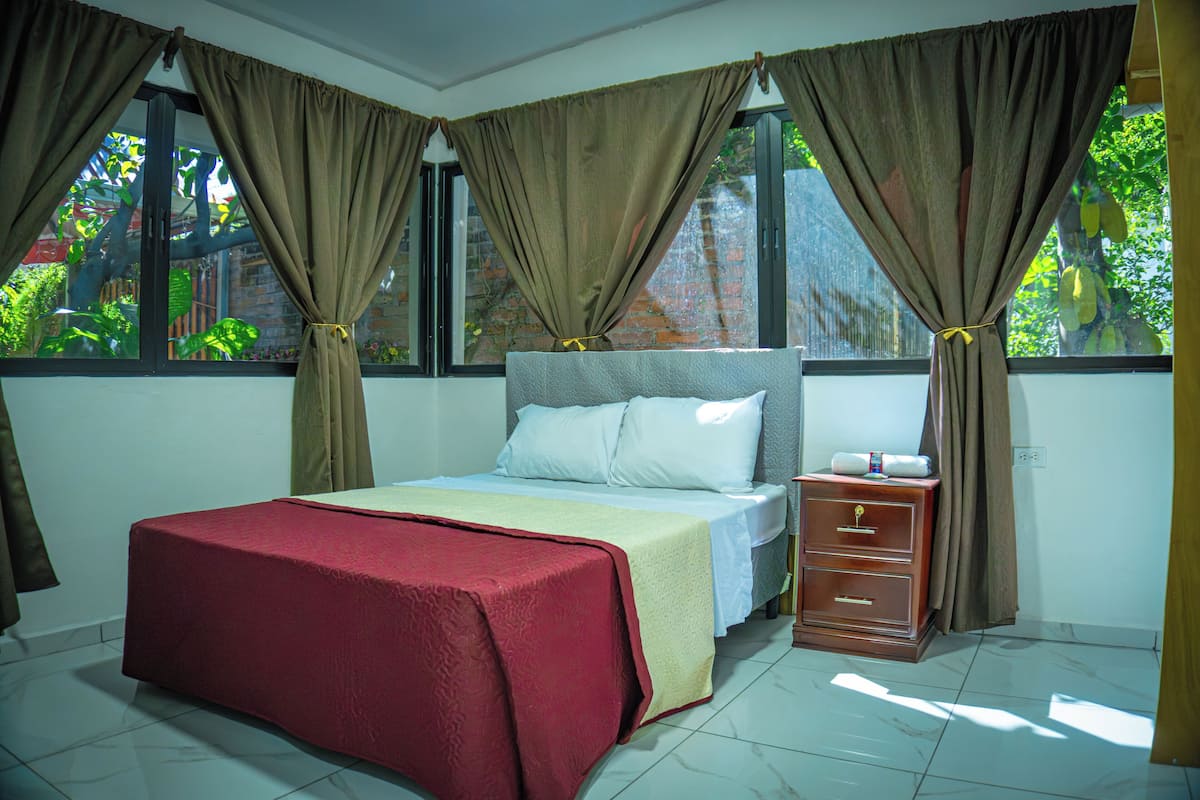 A bedroom with a bed, nightstand, and curtains.