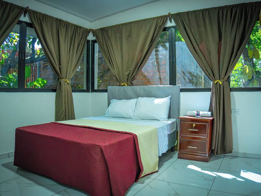 A bedroom with a bed, nightstand, and curtains.