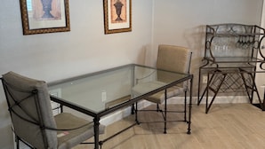 A dining area with a glass table, two chairs, and a hanging light fixture. - Beautiful Courtyard Villa near Lake Sumter Landing (The Villages)