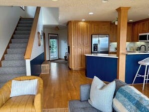 Eine moderne Küche mit Holzausstattung, einem Edelstahlkühlschrank und einer Bar.