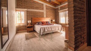 Une chambre à coucher avec une tête de lit en bois, un mur en briques et un lustre.