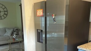 A modern kitchen with a stainless steel refrigerator, a blue cabinet, and a glass coffee table. - Perfect 2-bedroom building with AC in quaint Davie neighborhood (Davie)
