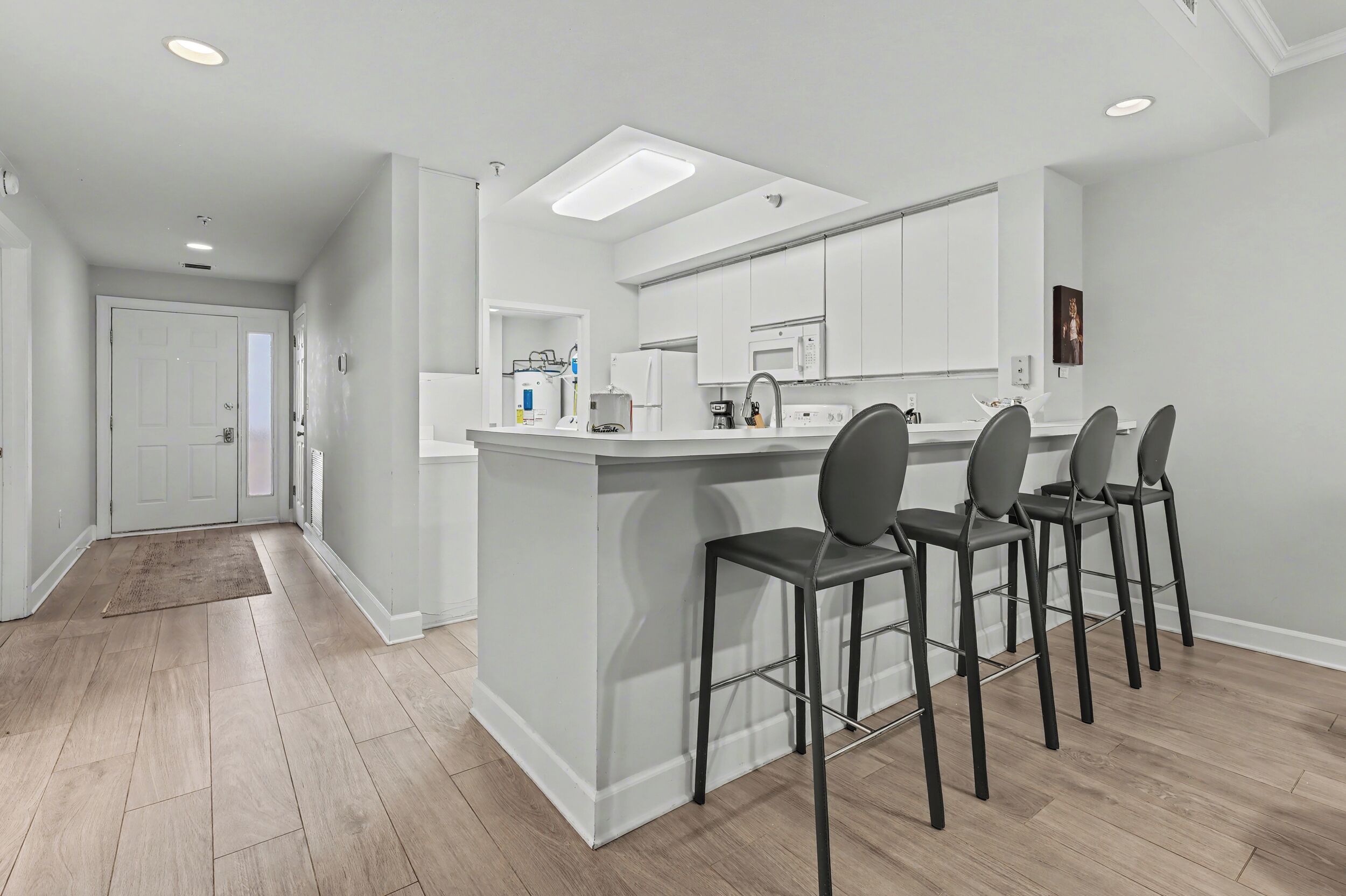 A modern kitchen with a central island, bar stools, and built-in appliances.