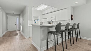 Una cocina moderna con una isla central, taburetes de bar y electrodomésticos integrados.