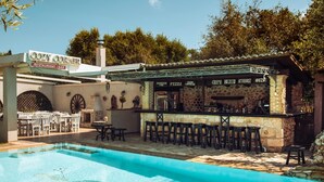 A poolside bar area with a sign reading 'Cozy Corner Restaurant Bar,' outdoor seating, and a clear blue pool. - Grantzaos Villas Zante (Agios Sostis)