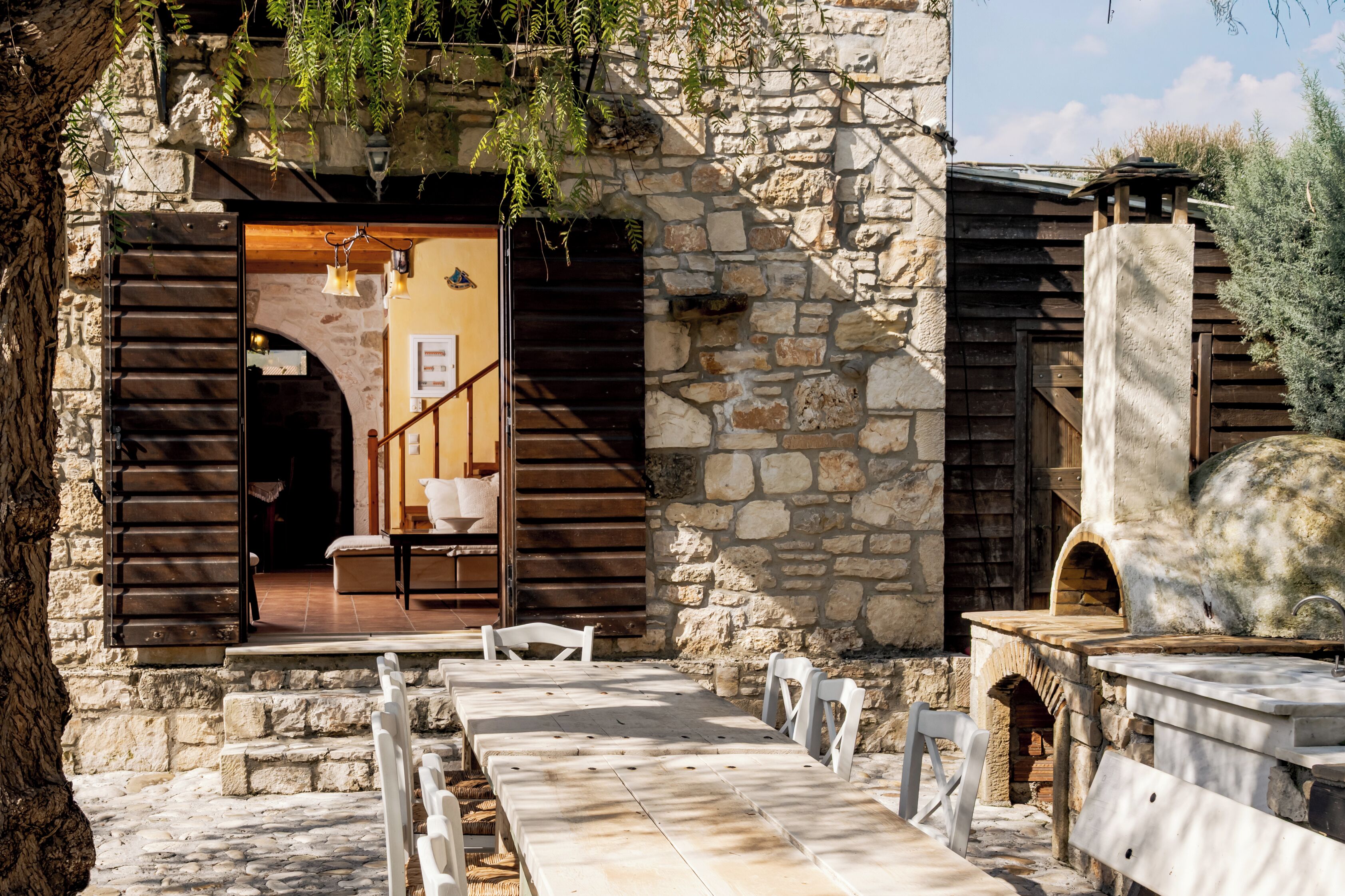 A stone building with a wooden staircase leading to a room with a bed and a table.