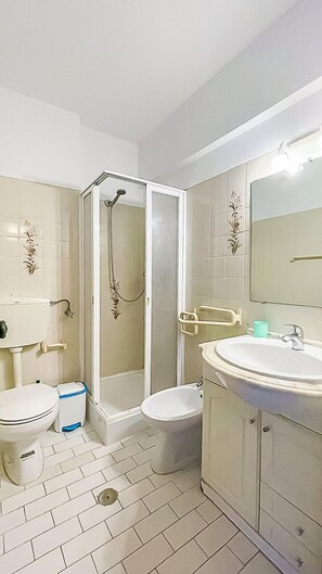 Une salle de bain équipée d’une douche, de toilettes, d’un bidet et d’un lavabo.