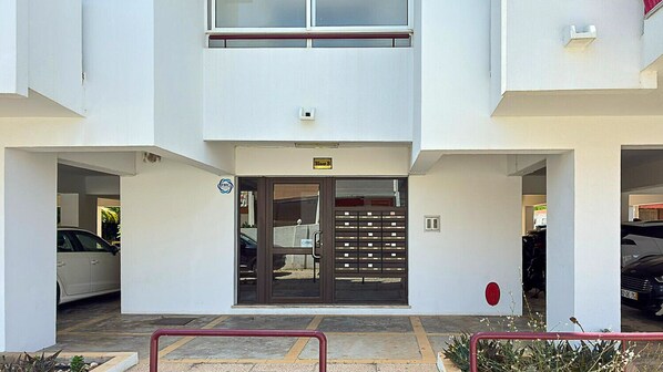 Un bâtiment moderne doté d’une double porte d’entrée, d’un espace de stationnement et d’un petit jardin agrémenté d’une rambarde rouge.