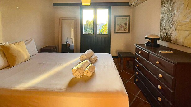 Une chambre d’hôtel avec un lit, une commode, une porte et une fenêtre donnant sur un paysage agréable.