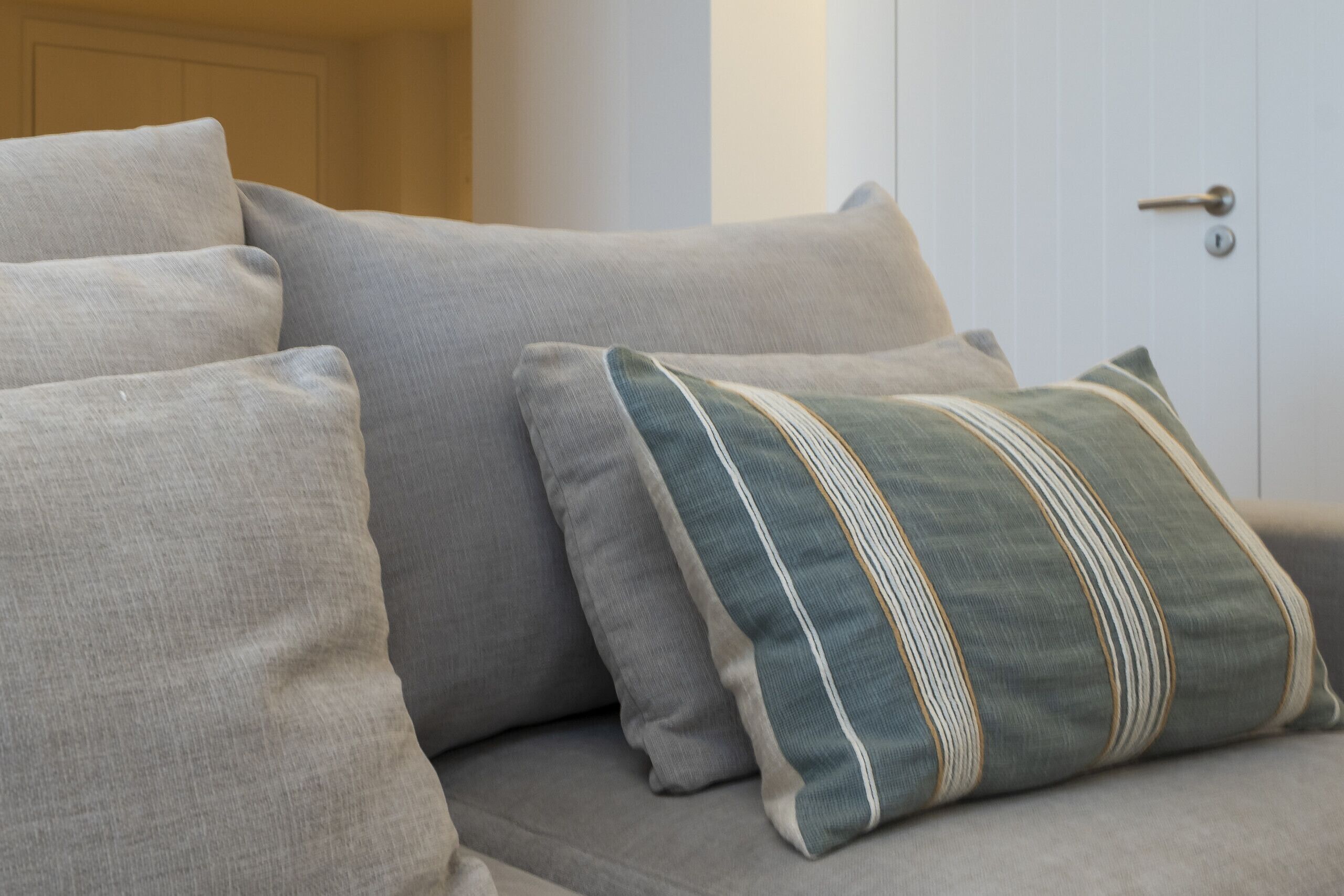 A grey sofa with multiple cushions, including a striped one.