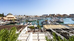 A marina with numerous boats docked, a building with a green roof, and a clear blue sky. - Vilamarina Elegance T2 Hsrentals Vilamarina (Loulé)