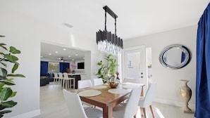 Un espace repas moderne avec une table en bois, des chaises blanches et un lustre décoratif.