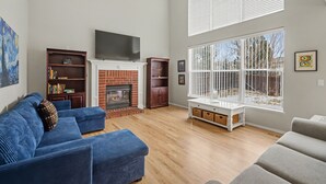 A living room with a fireplace, a television, and large windows. - Comfortable Cozy Retreat Prime North Location (Colorado Springs)