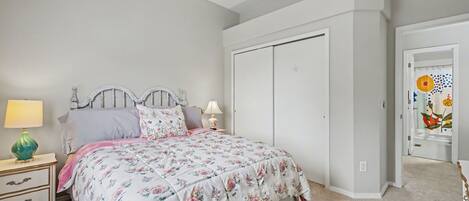 Un dormitorio con cama, mesitas de noche, ventilador de techo y armario.