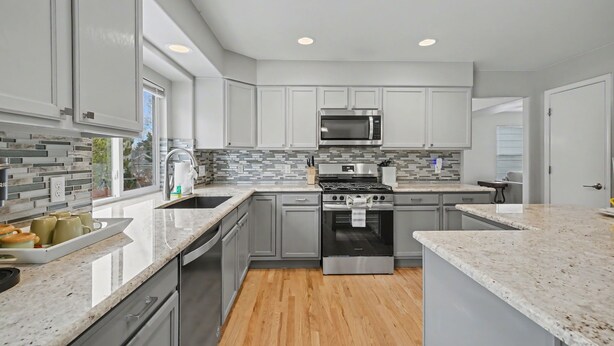 A modern kitchen with grey cabinets, a stainless steel microwave, a gas stove, and a dishwasher. - Comfortable Cozy Retreat Prime North Location (Colorado Springs)