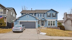 A two-story house with a garage, a driveway, and a parked car. - Comfortable Cozy Retreat Prime North Location (Colorado Springs)