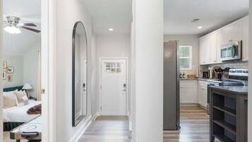 A modern kitchen with white cabinets, a microwave, and a refrigerator.