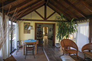 A dining area with a round table and chairs, a hanging light fixture, and a potted plant. - Gorgeous 7-bedroom farmhouse with AC in charming Soca (Departamento de Canelones)