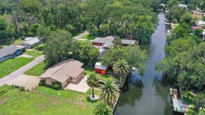Vue aérienne d’un quartier résidentiel avec des maisons, un canal et une végétation luxuriante.