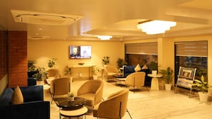 A modern lounge area with comfortable seating, a TV screen, and potted plants. - The Sea Valley Beach front Hotel (Puri)