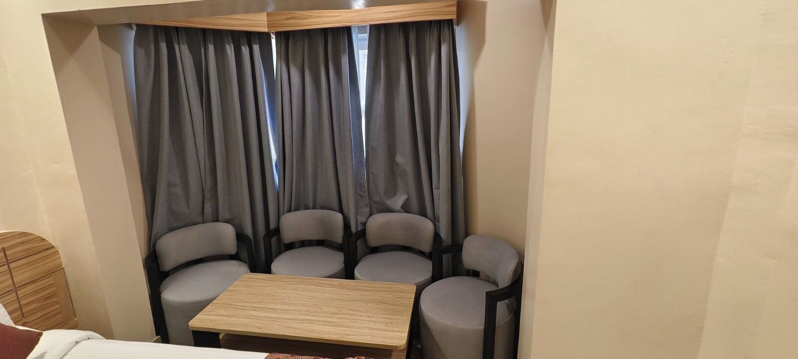A room with a bed, a small table, and four chairs arranged around it.