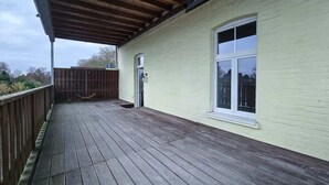 A wooden deck with a railing, a window, and a door on a building. - Alpha Apartments: 2BR + Terrace, Leafy District (Krefeld)