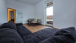 A modern room with a black sofa, a dining table with chairs, and a large window with a view. - Alpha Apartments: 2BR + Terrace, Leafy District (Krefeld)