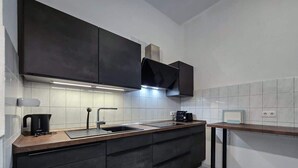 A modern kitchen with dark cabinetry, a stainless steel sink, and a wooden countertop. - Alpha Apartments: 2BR + Terrace, Leafy District (Krefeld)