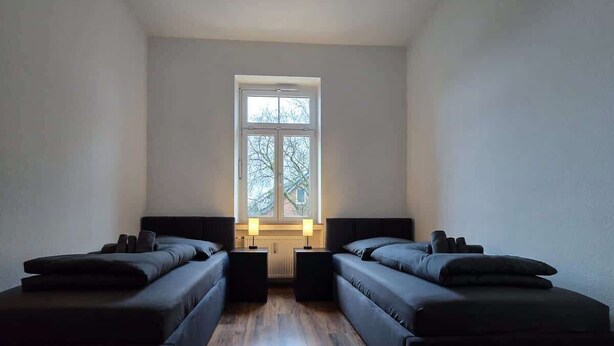 A room with two single beds, a window, and a radiator. - Alpha Apartments: 2BR + Terrace, Leafy District (Krefeld)