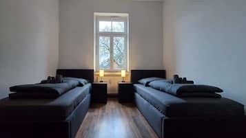 Ein Zimmer mit zwei Einzelbetten, einem Fenster und einer Heizung.