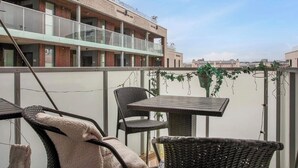 Une terrasse sur le toit, avec des fauteuils en osier, une table et des plantes en pot.