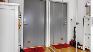 Une chambre d’hôtel avec une porte coulissante, un petit placard, un paillasson rouge et une paire de chaussures.
