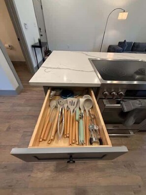 A kitchen with a drawer containing various utensils.