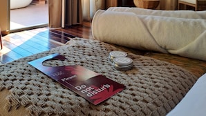 Hotelkamer met een groot bed, een zithoek met stoelen, uitzicht op palmbomen en een schuifdeur.'