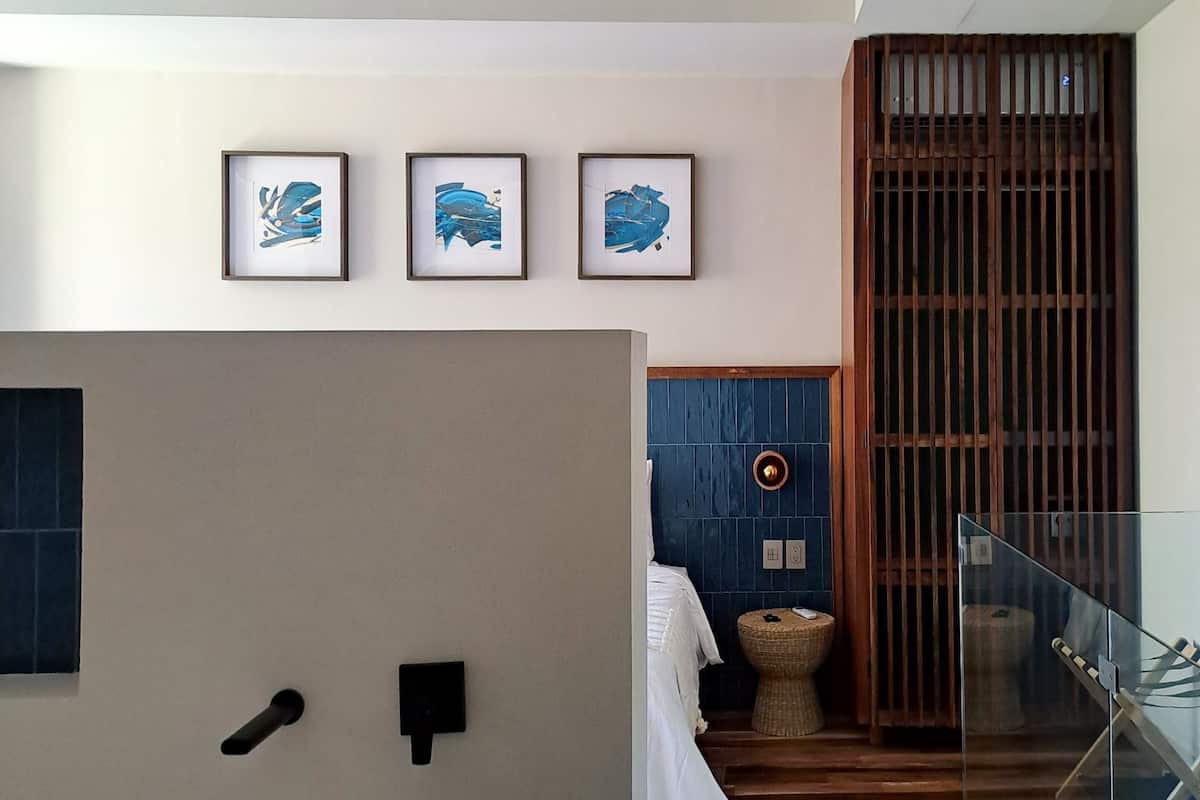 Un baño moderno con una bañera independiente, un ventilador de techo y tres cuadros abstractos en la pared.