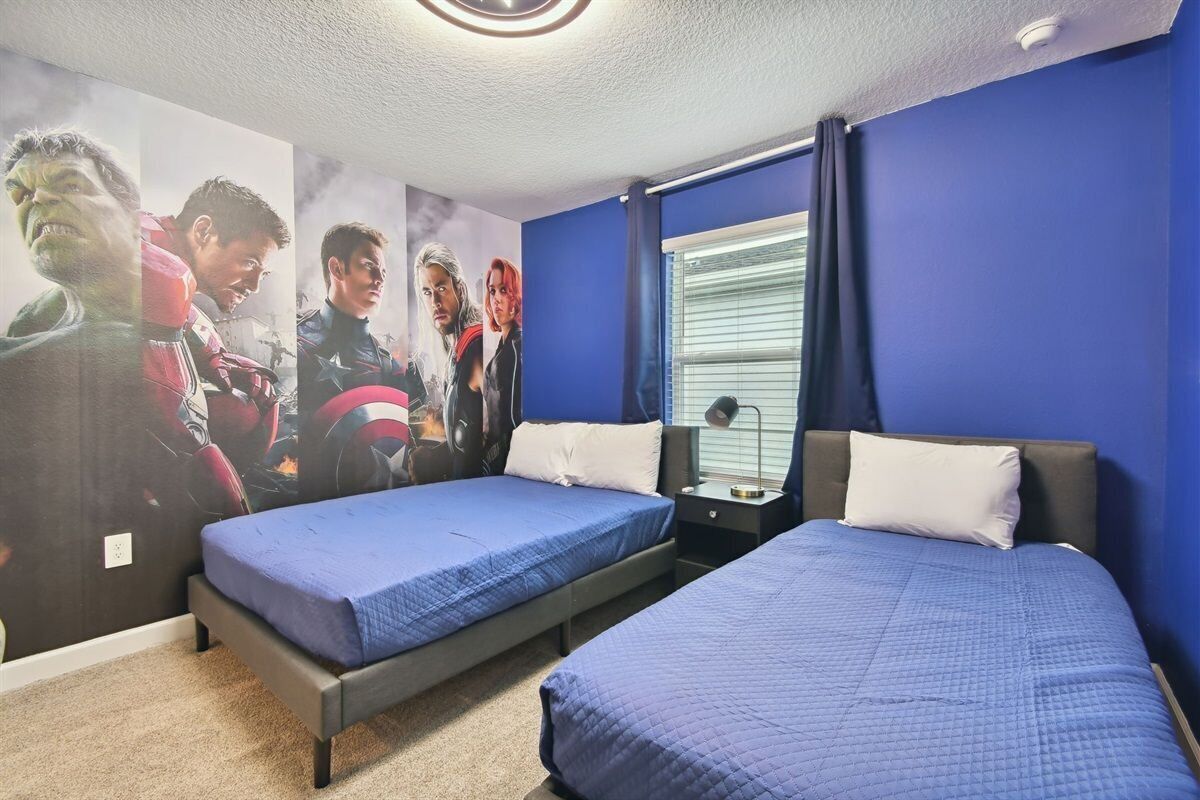 Una camera da letto con due letti, una finestra con tende e una parete con poster di film.