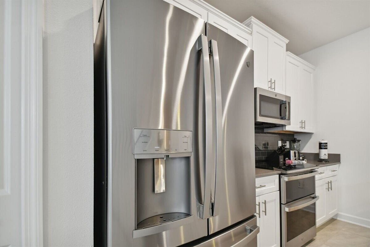 A modern kitchen with stainless steel appliances, including a refrigerator, microwave, and oven.